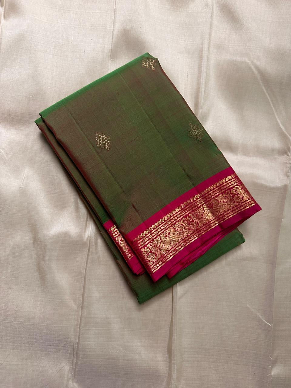 Folded olive green pure Kanchipuram silk saree with magenta zari woven border, available in the USA.
