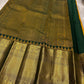 Close-up of gold zari woven border with deep green edging beside the red saree body on a light fabric background.