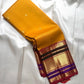 Mustard yellow Pure Kanchipuram Silk Saree with small gold buttas and wide zari border with maroon and purple accents.