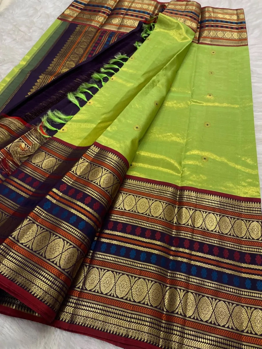 Handwoven fresh green tissue silk Kanchipuram saree with deep violet varisaipet contrast.