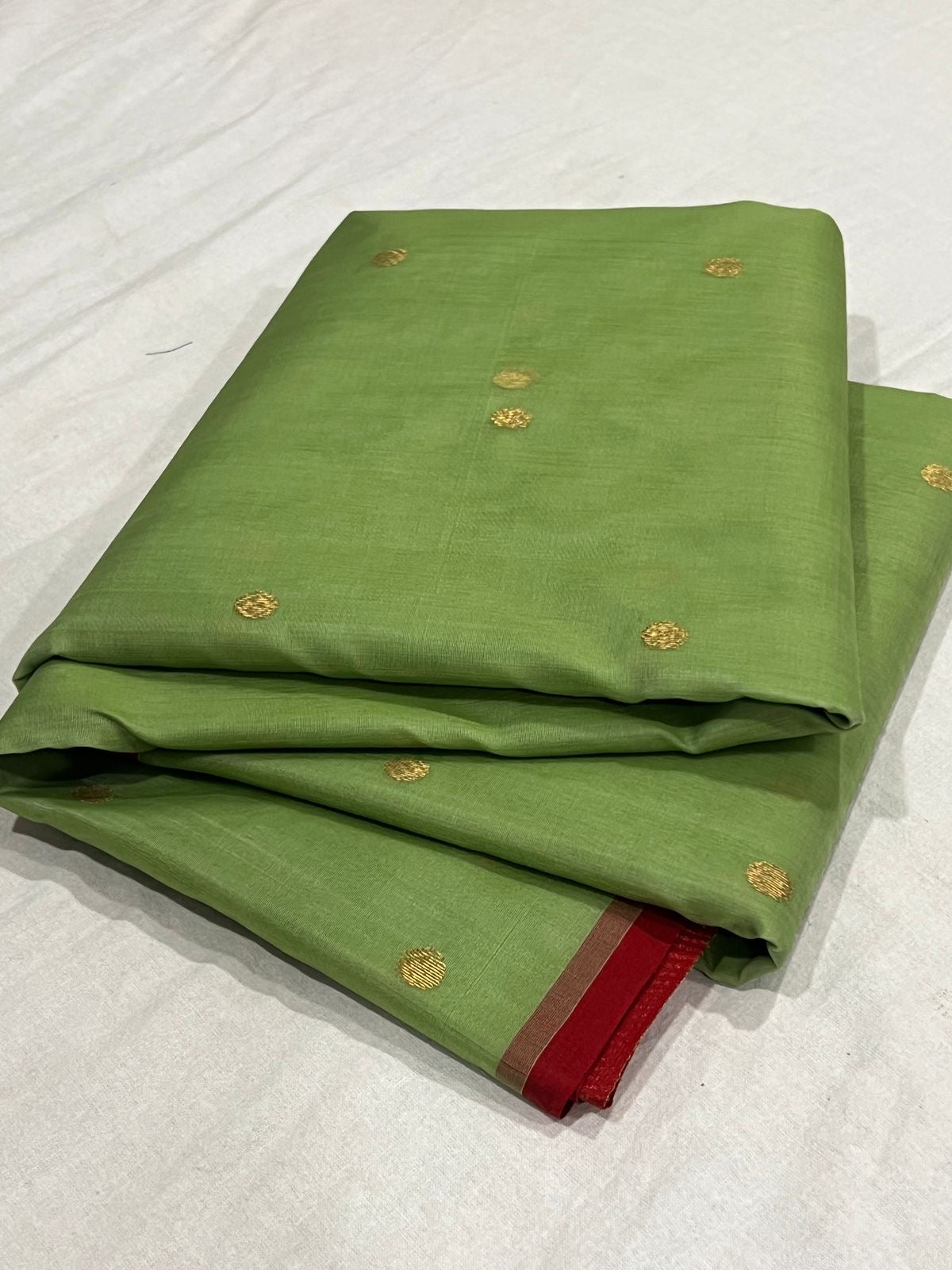 Folded green Chanderi Katan Silk saree with delicate gold woven buttas and deep red border