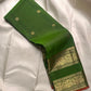 Angled display of fresh leaf green × rust orange handwoven Rettapet Kanchipuram silk with gold zari bands and Mayil Chakram buttas
