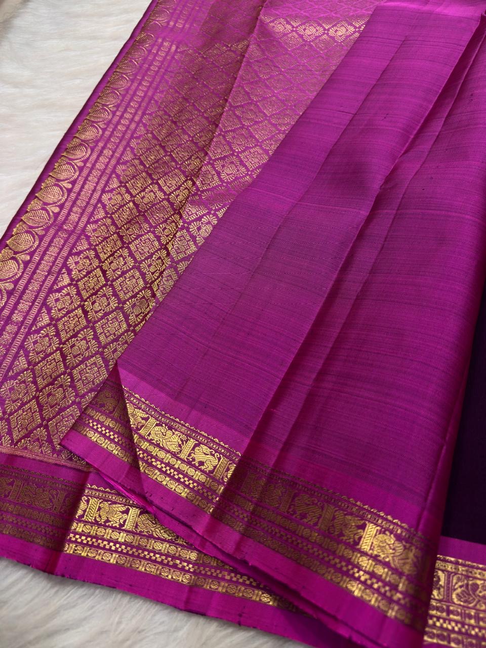 Close view of deep violet pure silk meeting a vivid pink figurative classic-gold zari border.