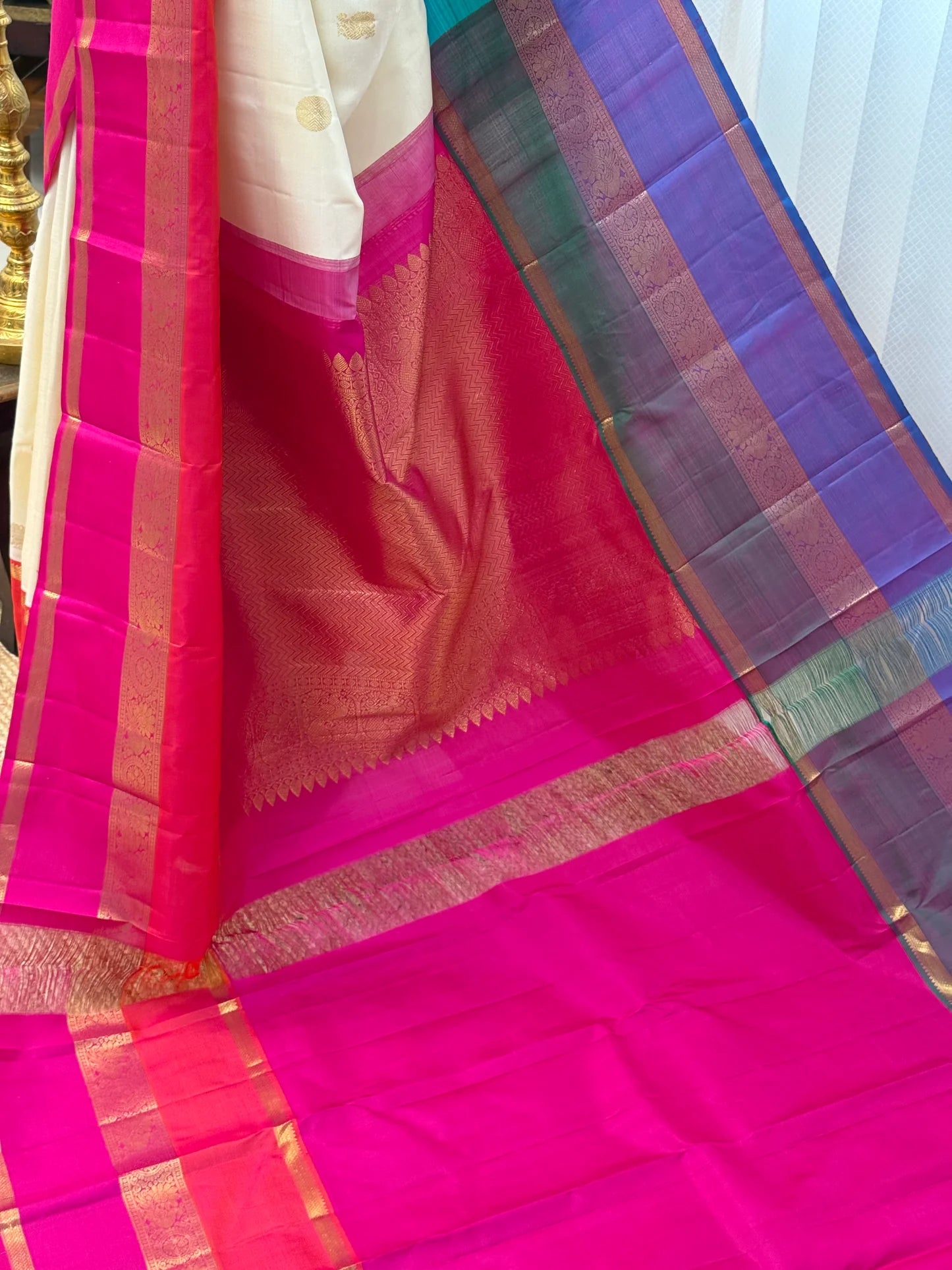 Close pleats of ivory saree with red-hot pink contrast border and zari woven edging, shown beside pink pallu.
