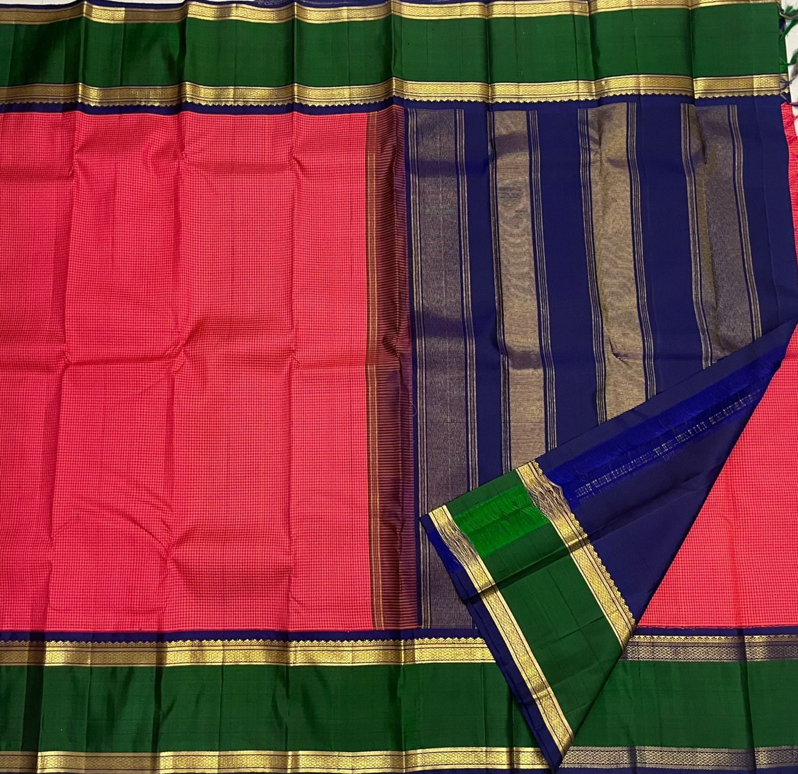 Close view of red checked pure Kanchipuram silk saree with green and navy zari border, folded ends shown, available in the USA.