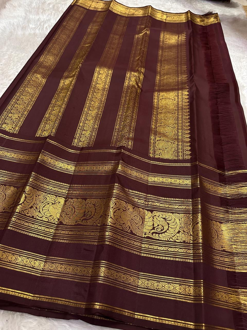 Gold Gandaberunda motifs woven in a repeating arrangement on the olive-green silk body.