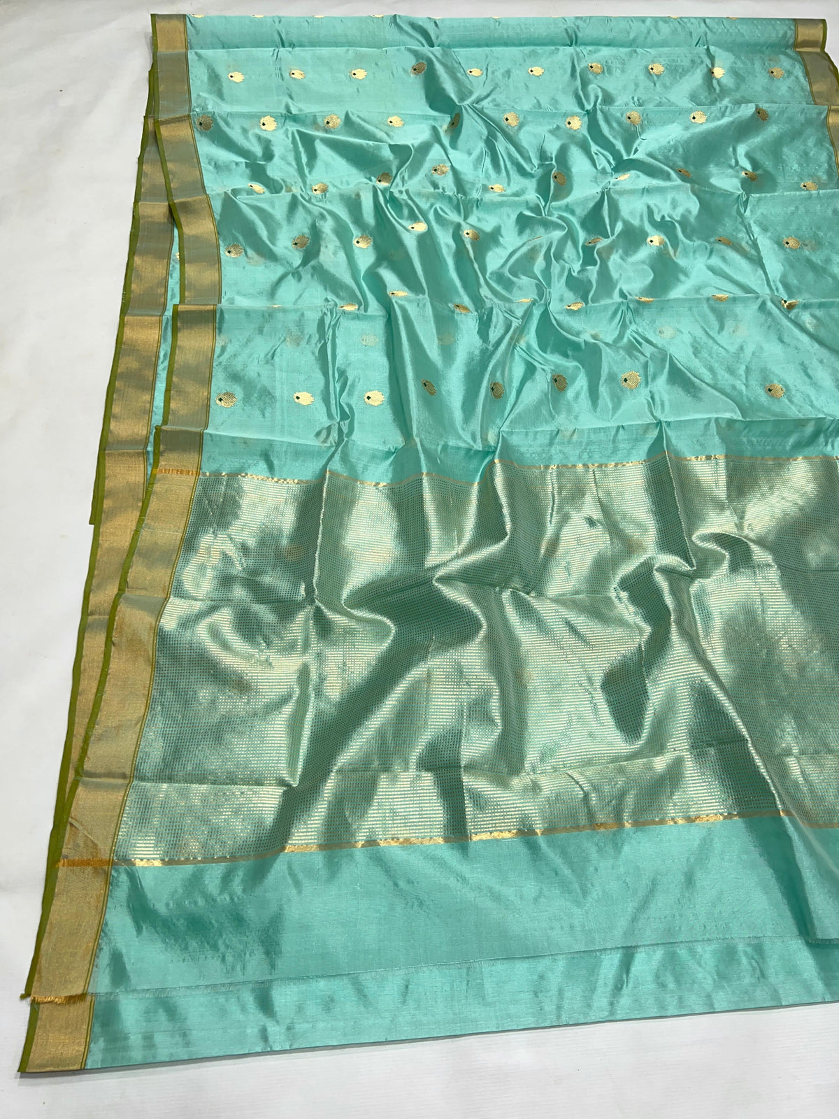 Detail of petite gold-toned buttas with tiny dark green accents on an Aqua Blue Katan Silk Chanderi saree