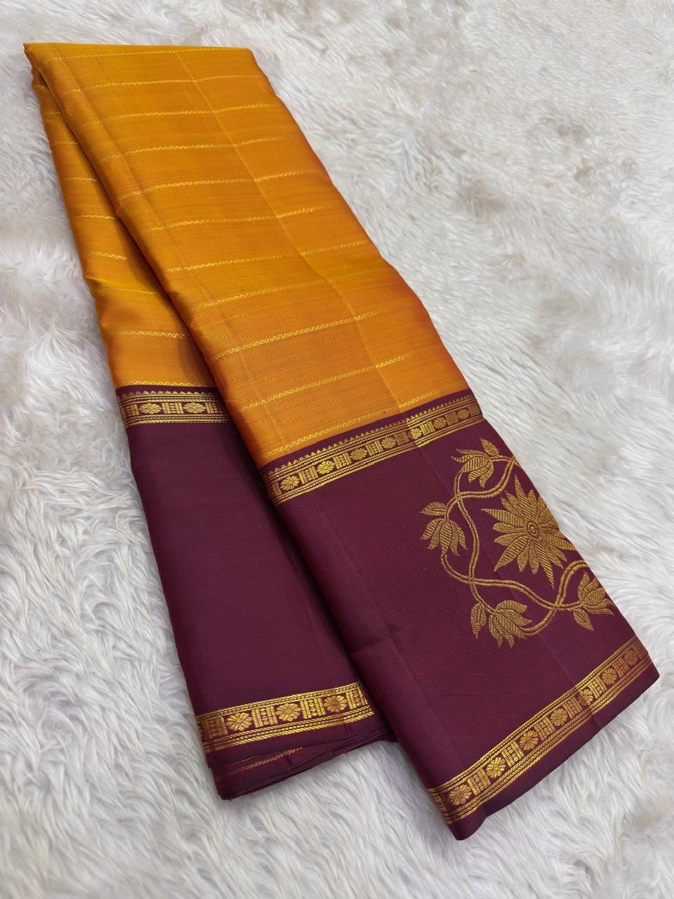 Full view of turmeric gold Kanchipuram saree with floral border and rich layered pallu.