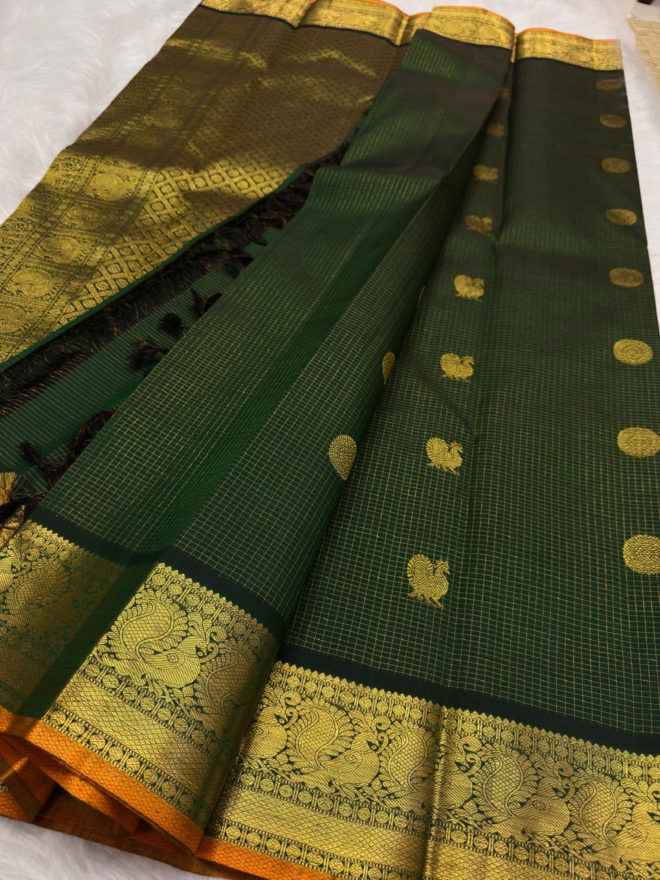 Close detail of bird-inspired gold zari buttas and round ornamental medallions within the fine checked body.