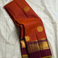 Folded rust orange Pure Kanchipuram silk saree with deep purple border and gold zari woven detailing