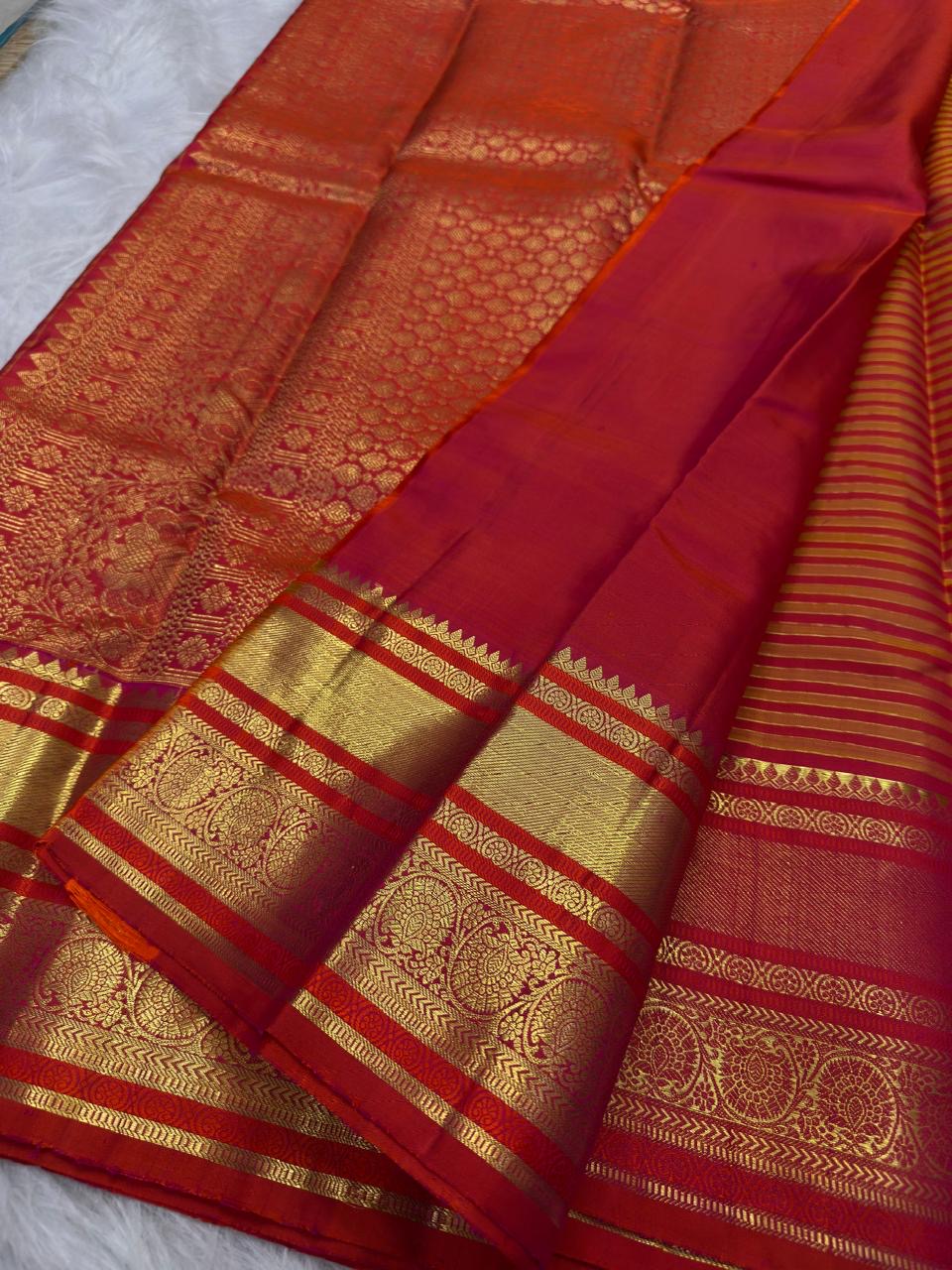 Detailed vermilion-red and gold contrast border with ornamental kodi butta work and gold zari bands.