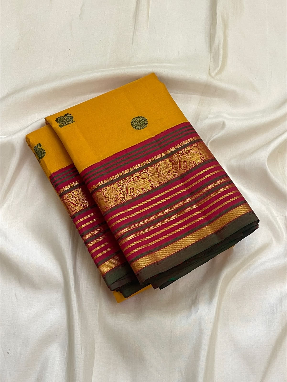 Close-up of yaanai (elephant) silk thread buttas on the golden turmeric Kanchipuram saree.
