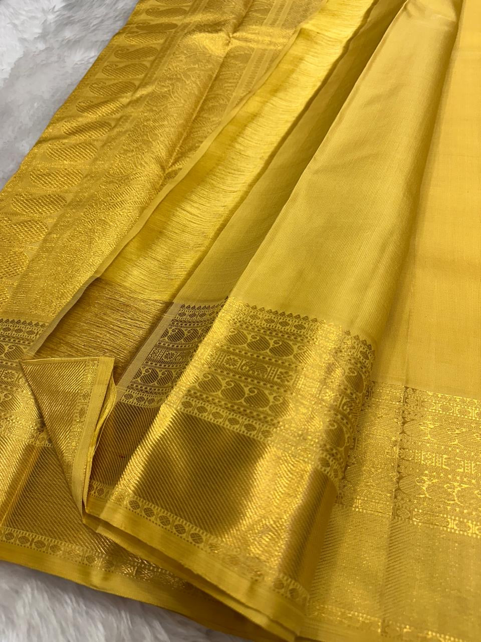 Close view of curved gold zari buttas woven across the Butter Yellow silk body