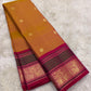 Golden mustard Butta Kanchi Pattu saree with floral gold motifs and magenta-green zari border