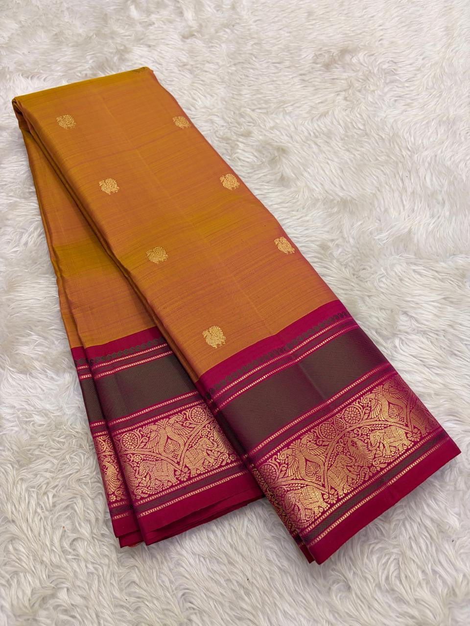 Golden mustard Butta Kanchi Pattu saree with floral gold motifs and magenta-green zari border