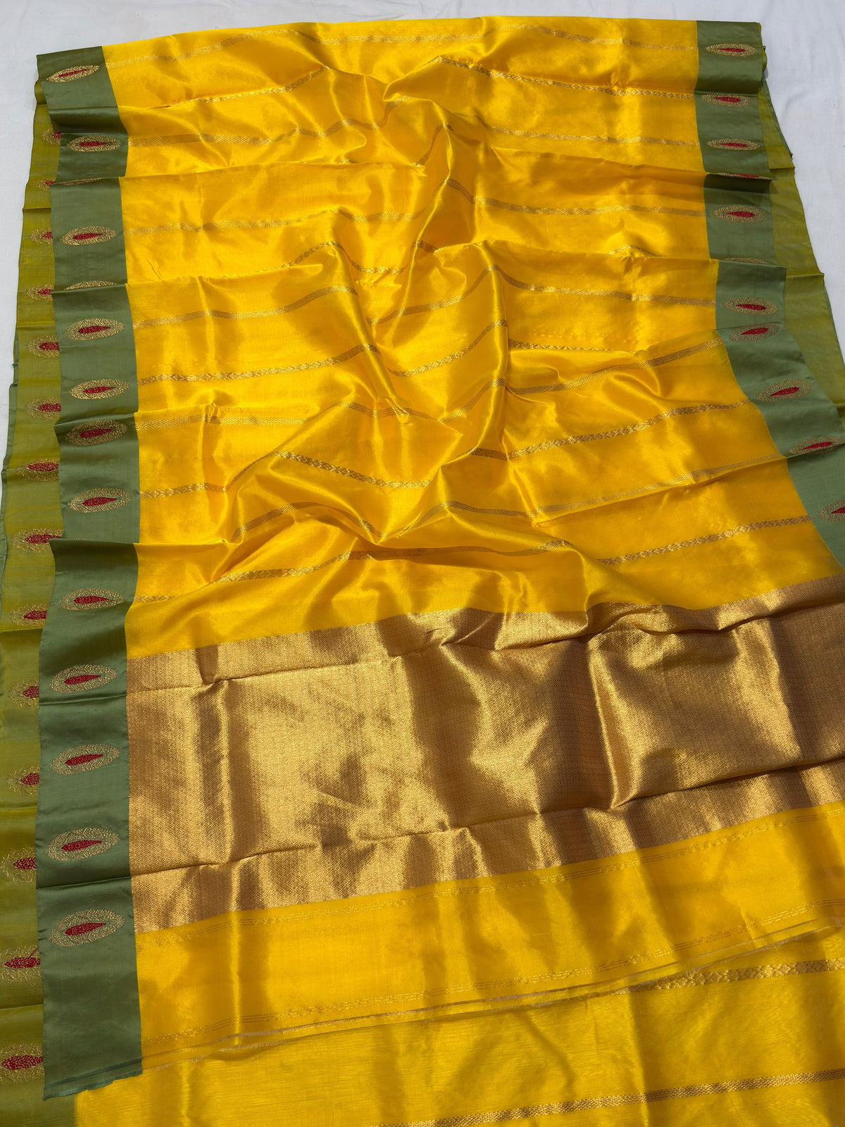 Crimson and gold decorative motifs on green saree border