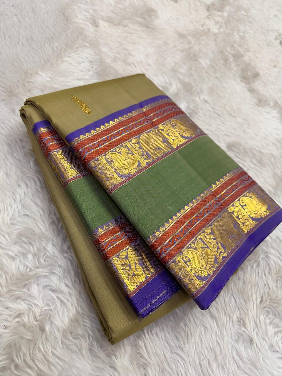 Moss Green Shot Silk pure silk Kanchipuram saree, silk body, showing muted olive-moss and sage green shot with golden undertones, brighter emerald pallu, deep cobalt-blue silk-thread accents, copper-rust bands and antique-gold zari
