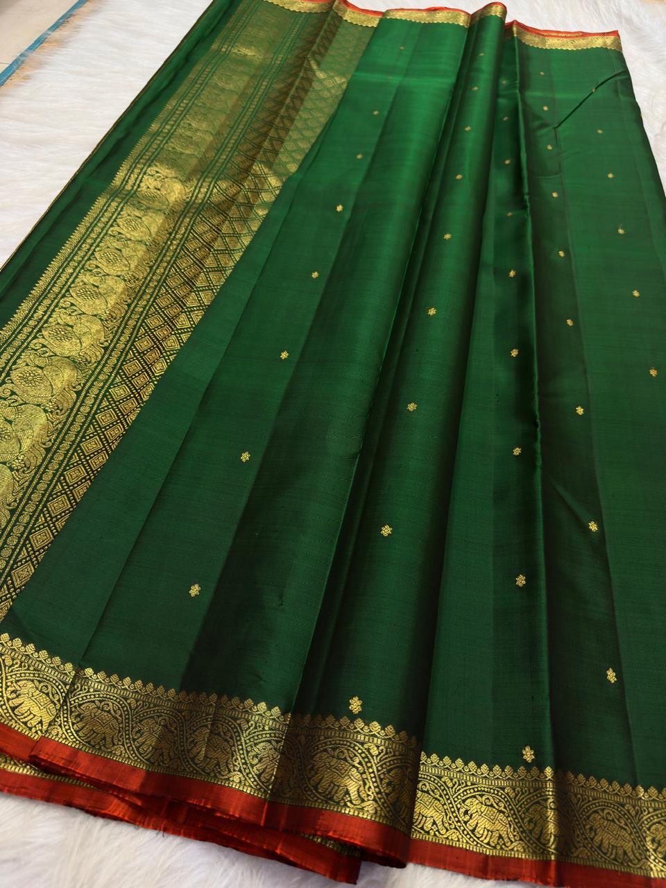 Close view of antique-gold zari buttas on Deep Emerald Green Kanjivaram silk.