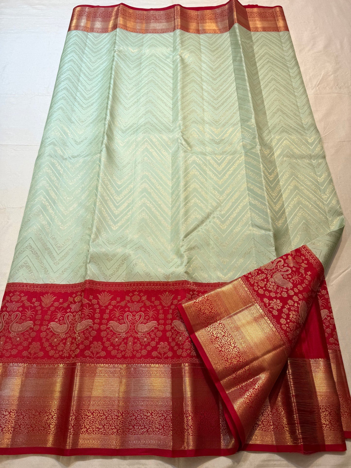 Pista green Butta Kanchipuram silk saree draped, showing the red contrast border