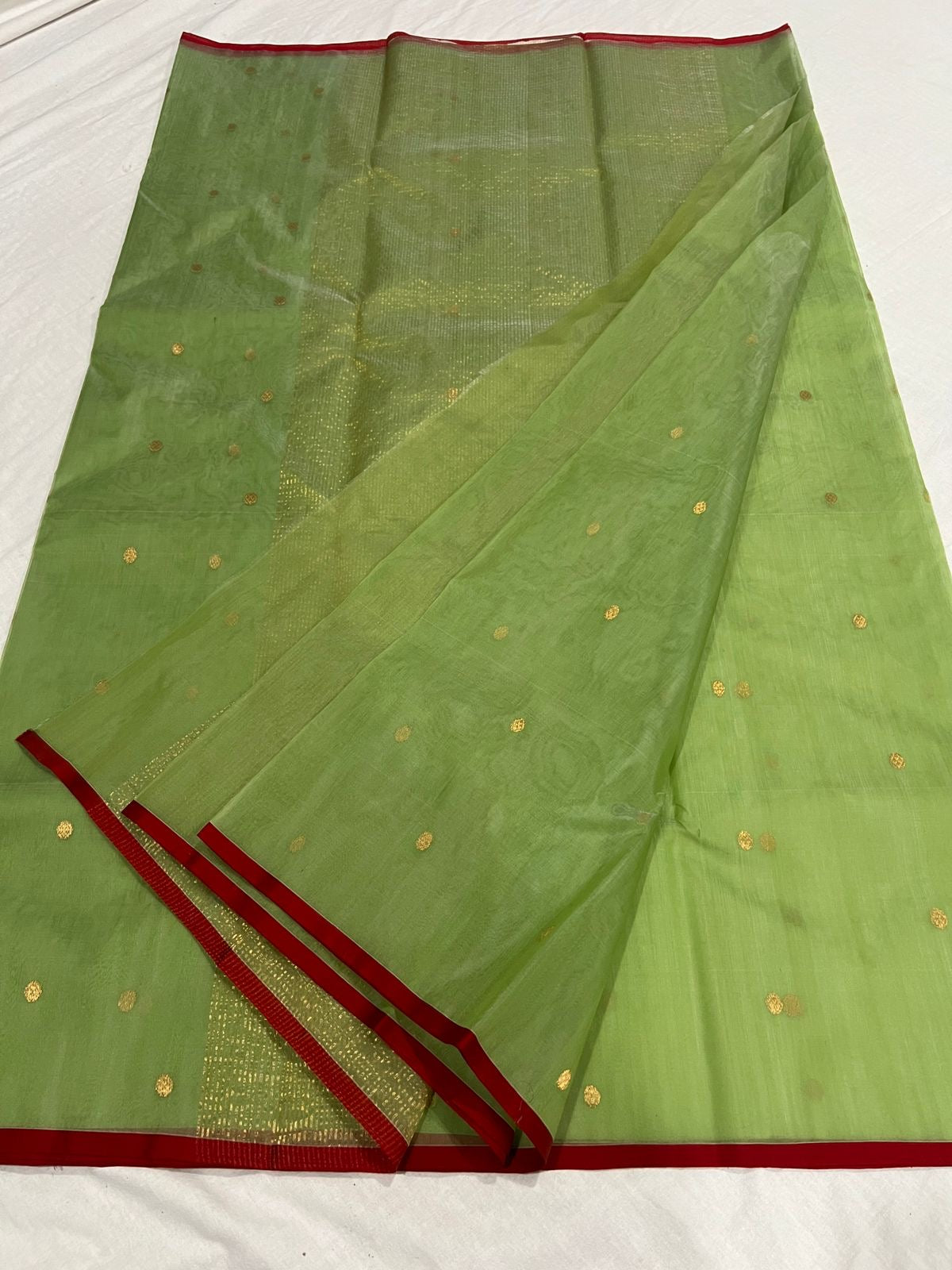 Green handloom Chanderi silk saree showing gold buttas and slender red silk border