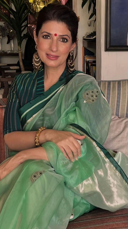 Woman seated indoors wearing a soft green pure silk Chanderi saree with a translucent body and fine zari edge