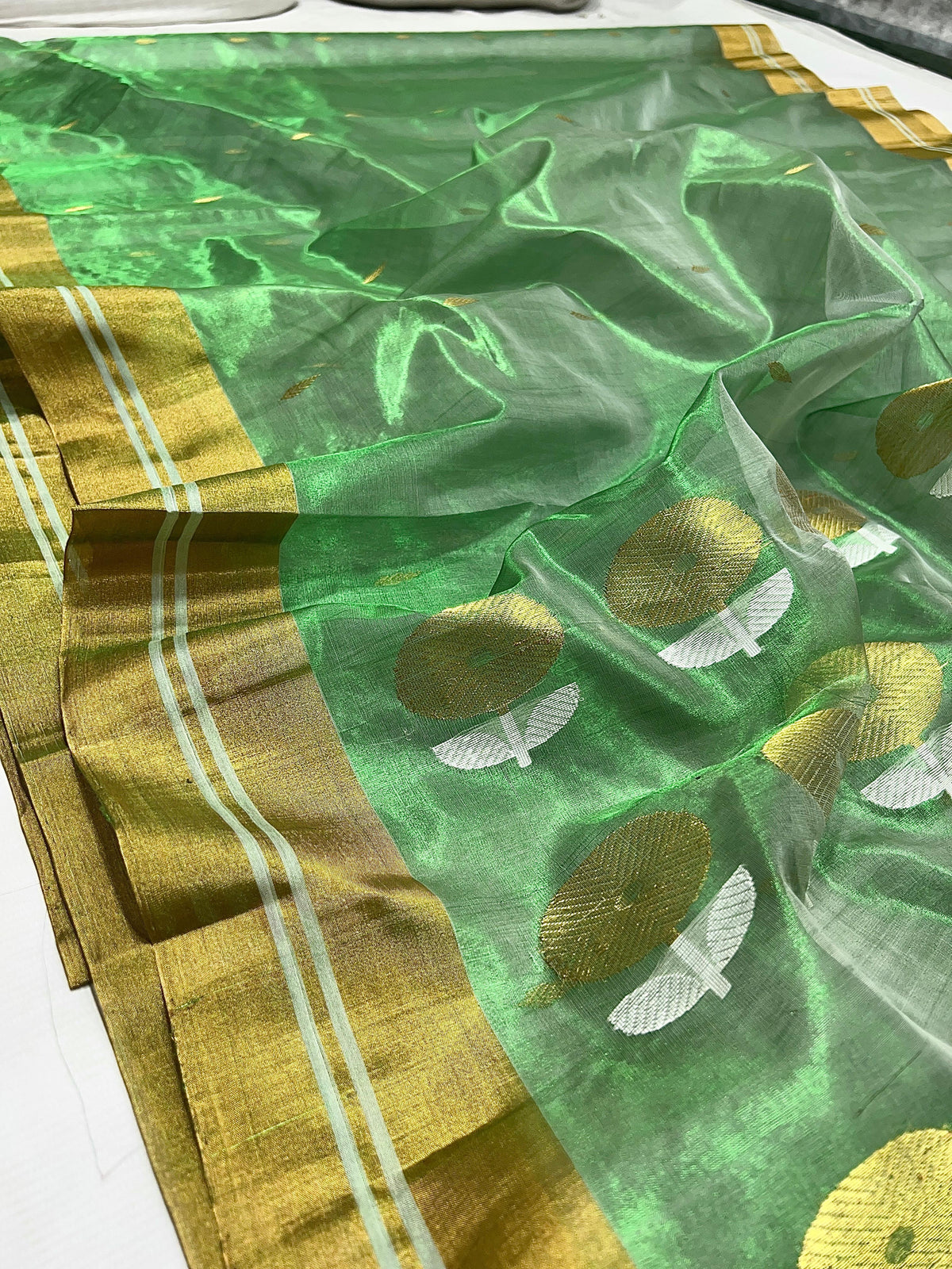 Broad metallic gold border with pale stripes on green Chanderi silk