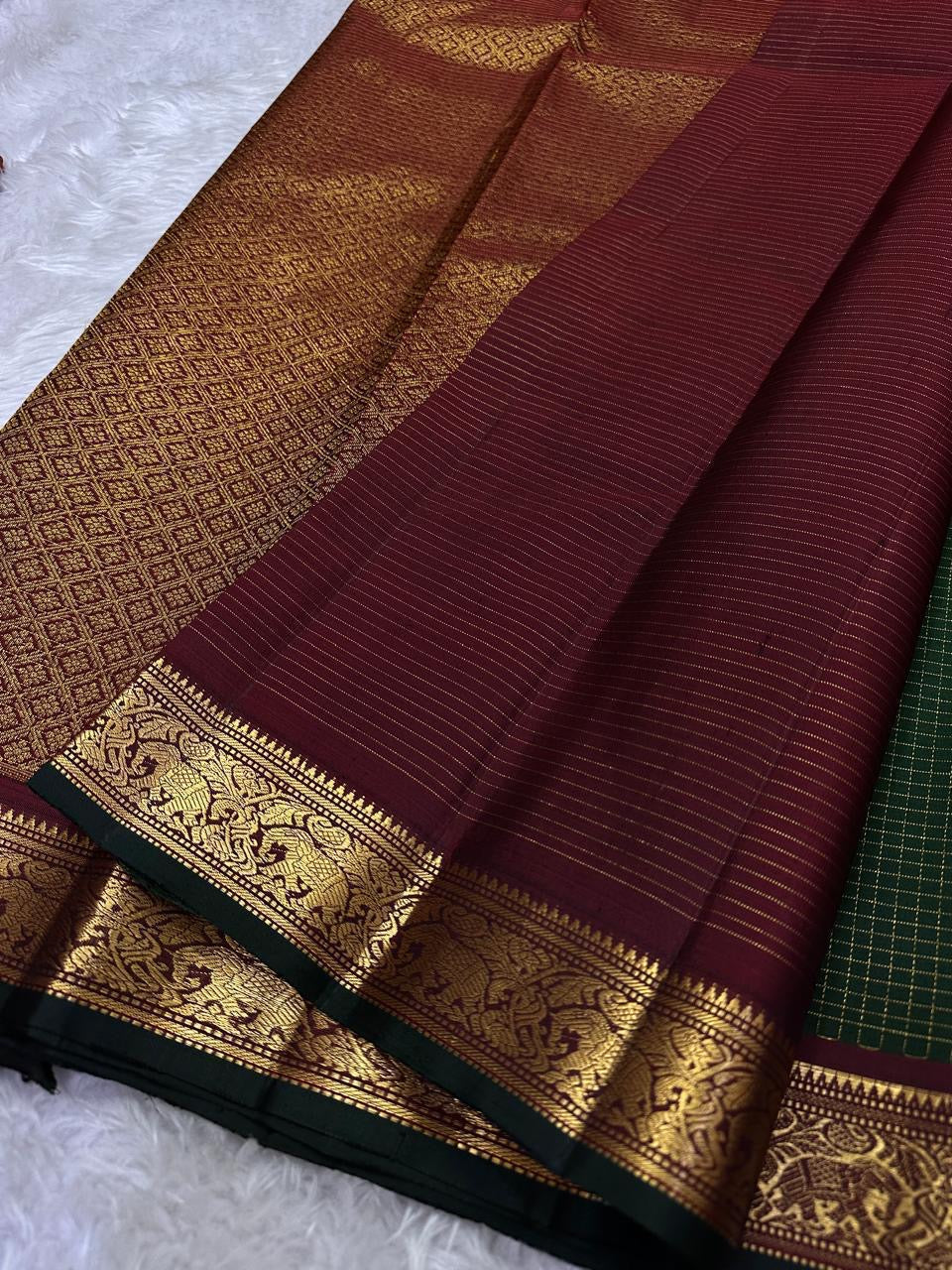 Close-up of maroon pallu with fine lines and gold zari woven elephant border