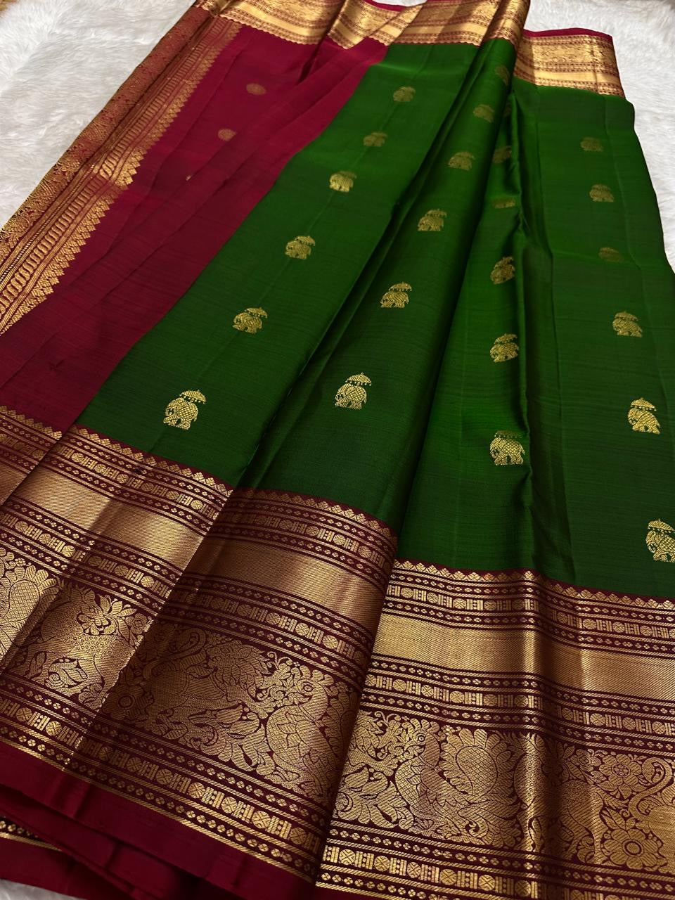 Arakku and gold zari border on a deep green Kanchipuram saree with elephant buttas.