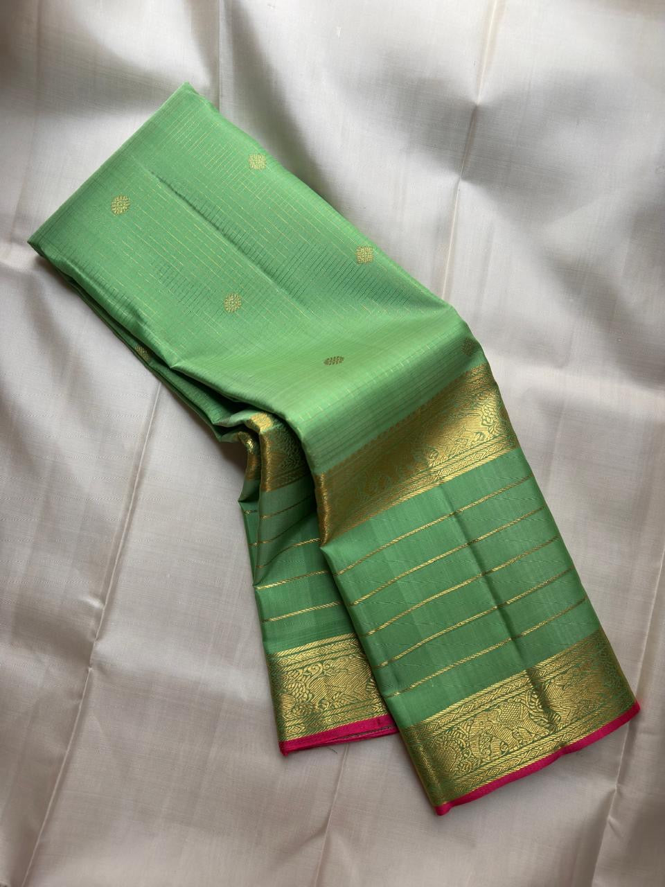 Fresh parrot-green Kanchipuram silk body with a fine classic-gold Zari Kattam grid and open silk field.
