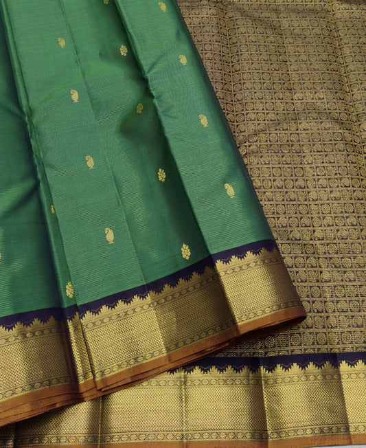 Emerald green Pure Silk Kanjipuram saree with spaced gold zari buttas and a deep navy gold zari border.