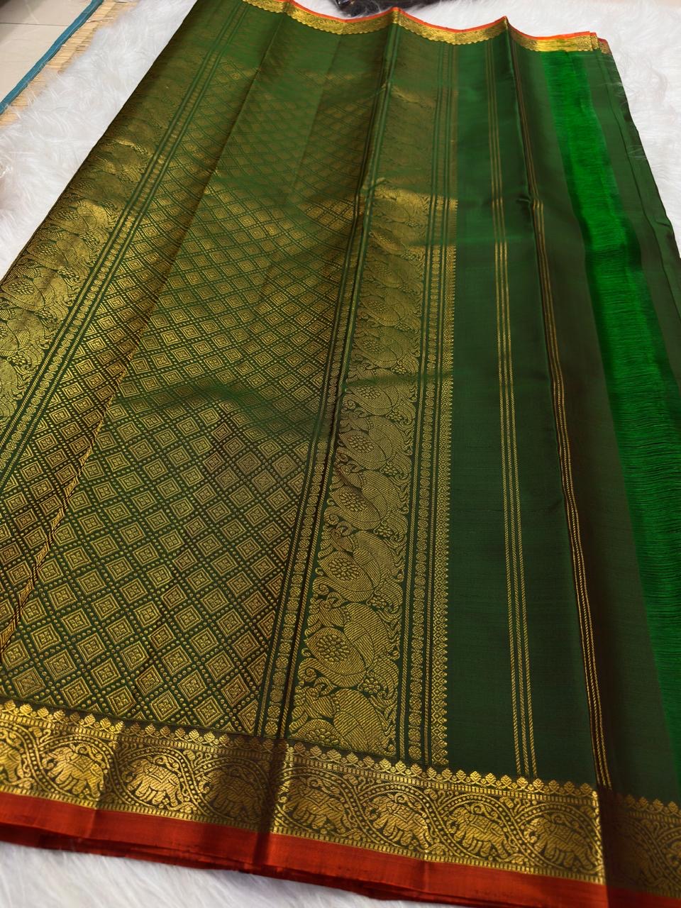 Kanchipuram border with repeated gold zari Yaanai elephant motifs and warm rust-red silk edge.