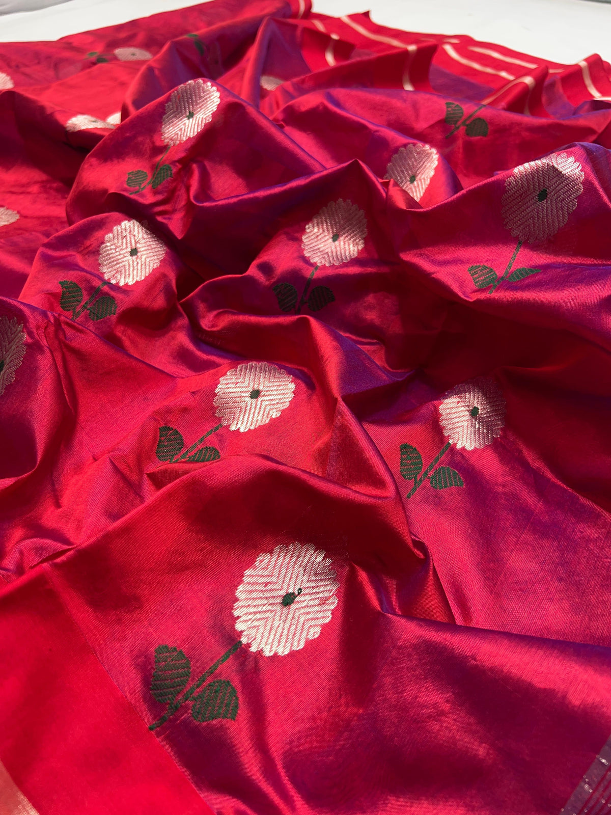 Detail of green leaf accents woven into the silver floral buttas on the Raspberry Red Chanderi saree