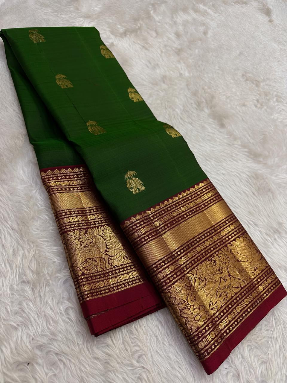 Deep green Kanchipuram silk with individually spaced gold-zari Yaanai Ambari elephant buttas.