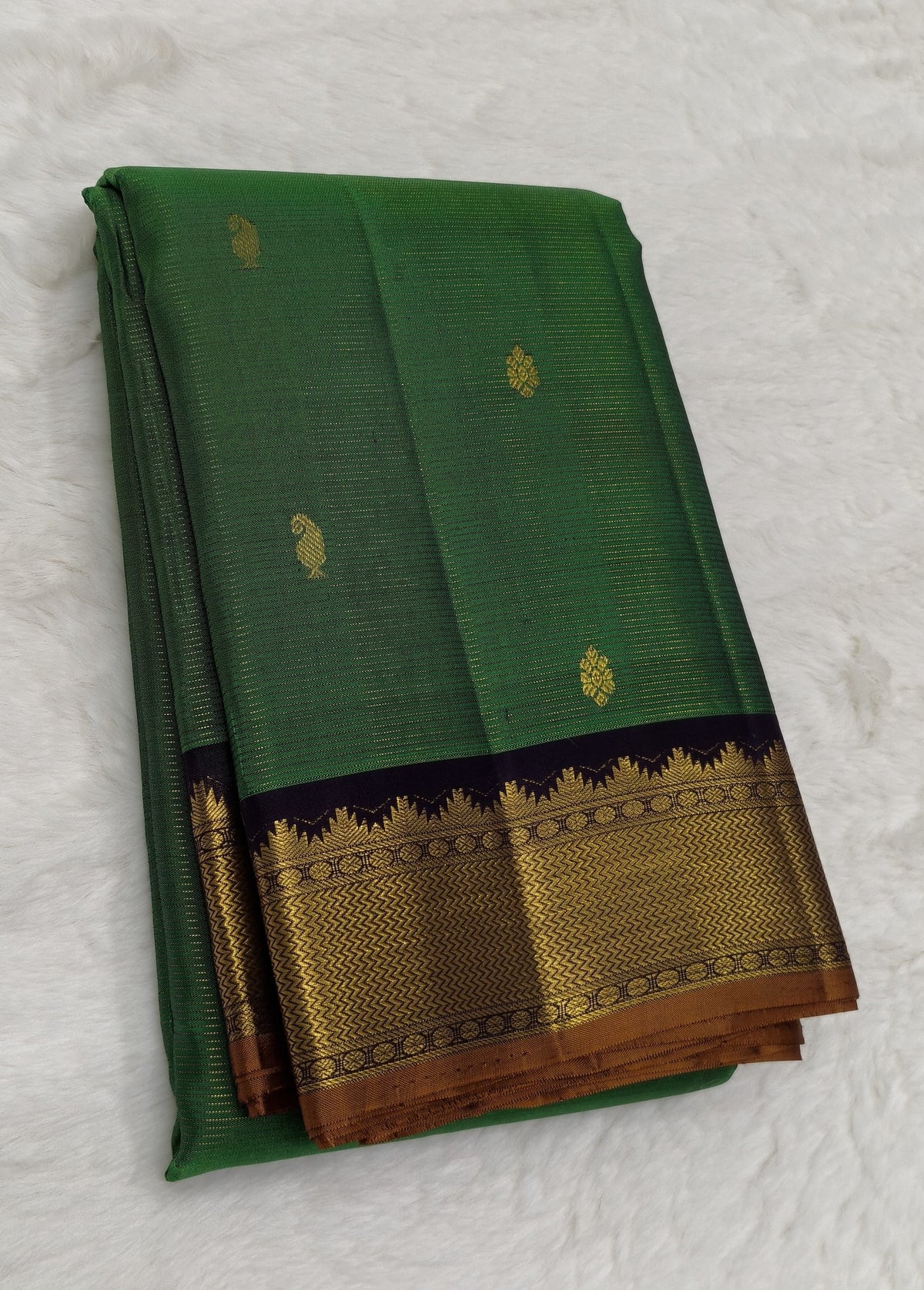 Close view of Maragatham green silk body woven with fine gold oosi lines and small individually spaced zari buttas.