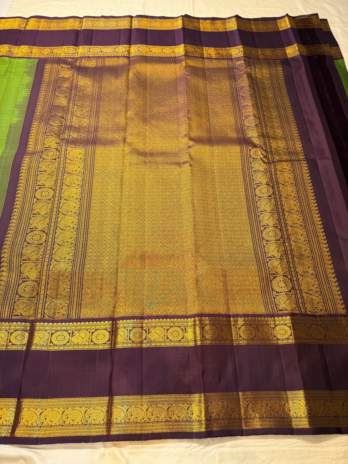 Full view green Pure Kanchipuram silk saree with scattered gold woven motifs and wide purple zari woven elephant border
