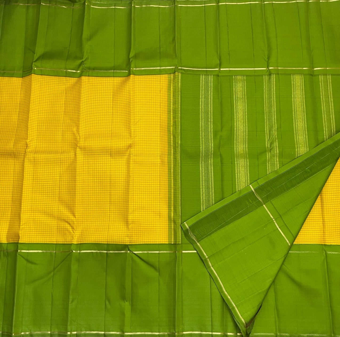 Close view of green Pure Kanchipuram silk saree with vertical zari woven stripes beside yellow micro-check panel