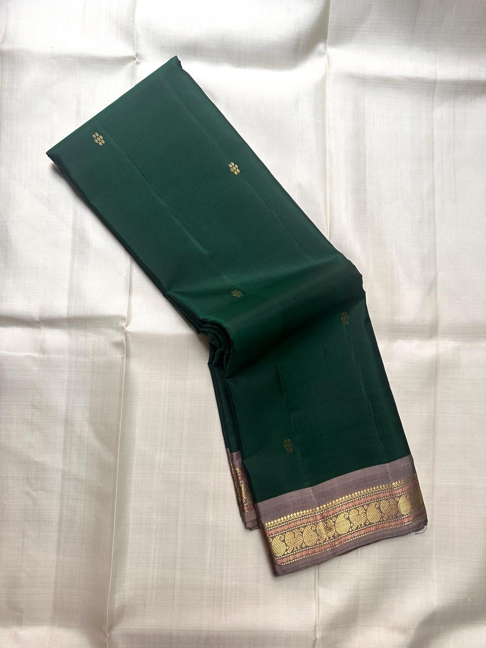 Pure Kanchipuram silk saree angled view highlighting small gold butta placement on green body