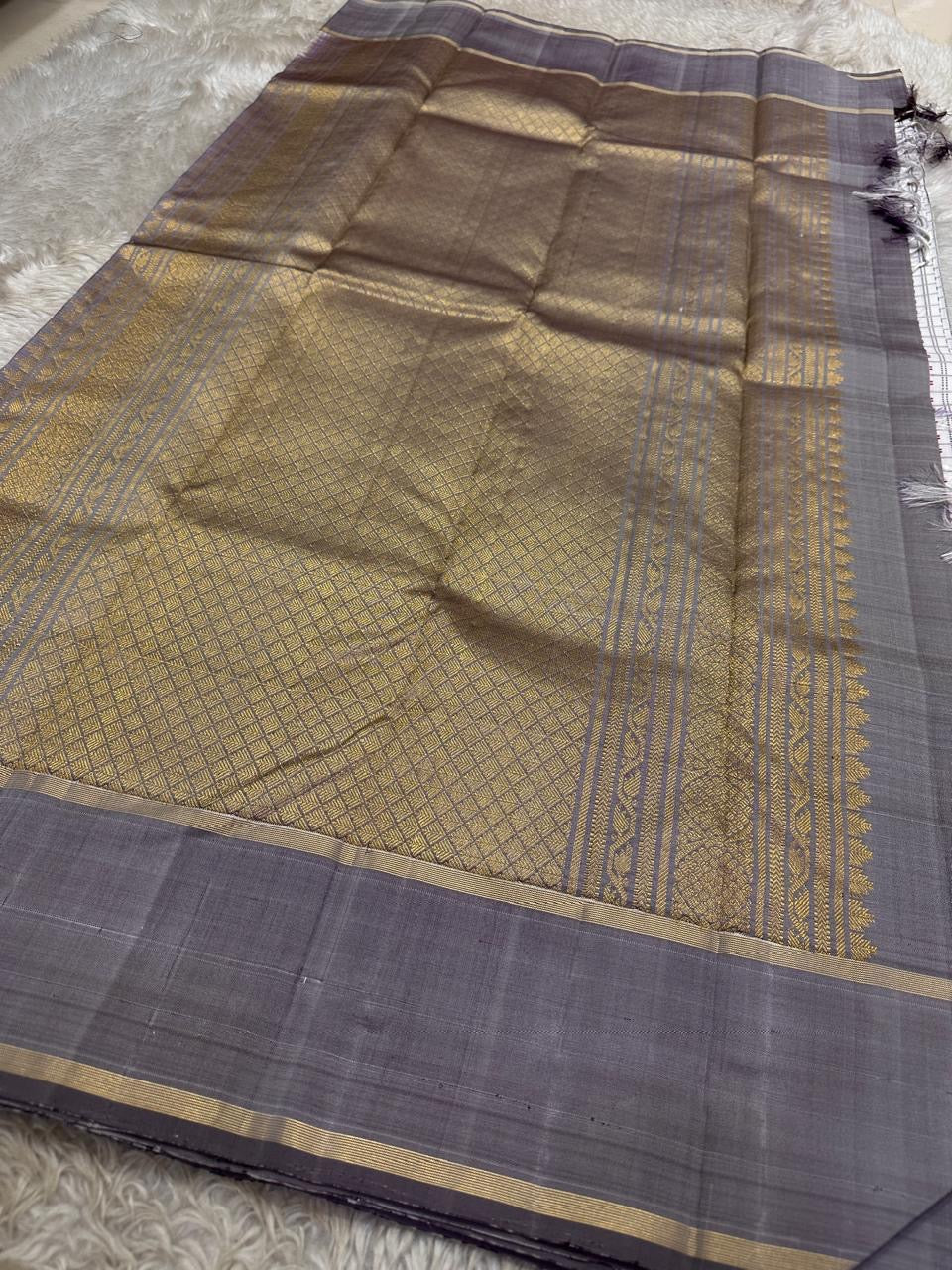 Folded pure Kanchipuram silk saree highlighting the ivory checked body with delicate dotted motifs and soft grey border finished with fine gold zari lines.