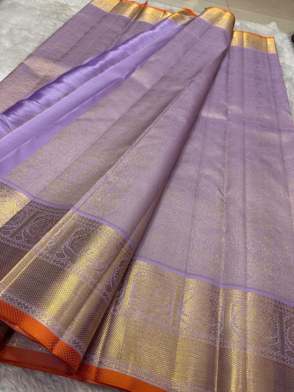 Spread lavender pure Kanchipuram silk saree with gold zari border and orange selvedge, shown available in the USA.