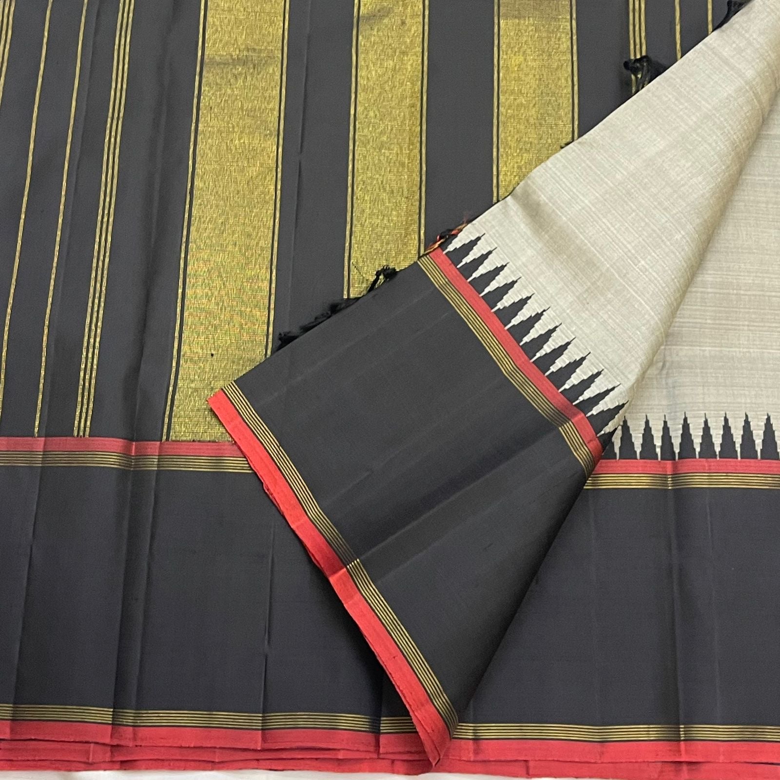 Full flat lay of Pure Kanchipuram silk saree with grey body, black border, red selvedge, and pillayar reku along the edge.