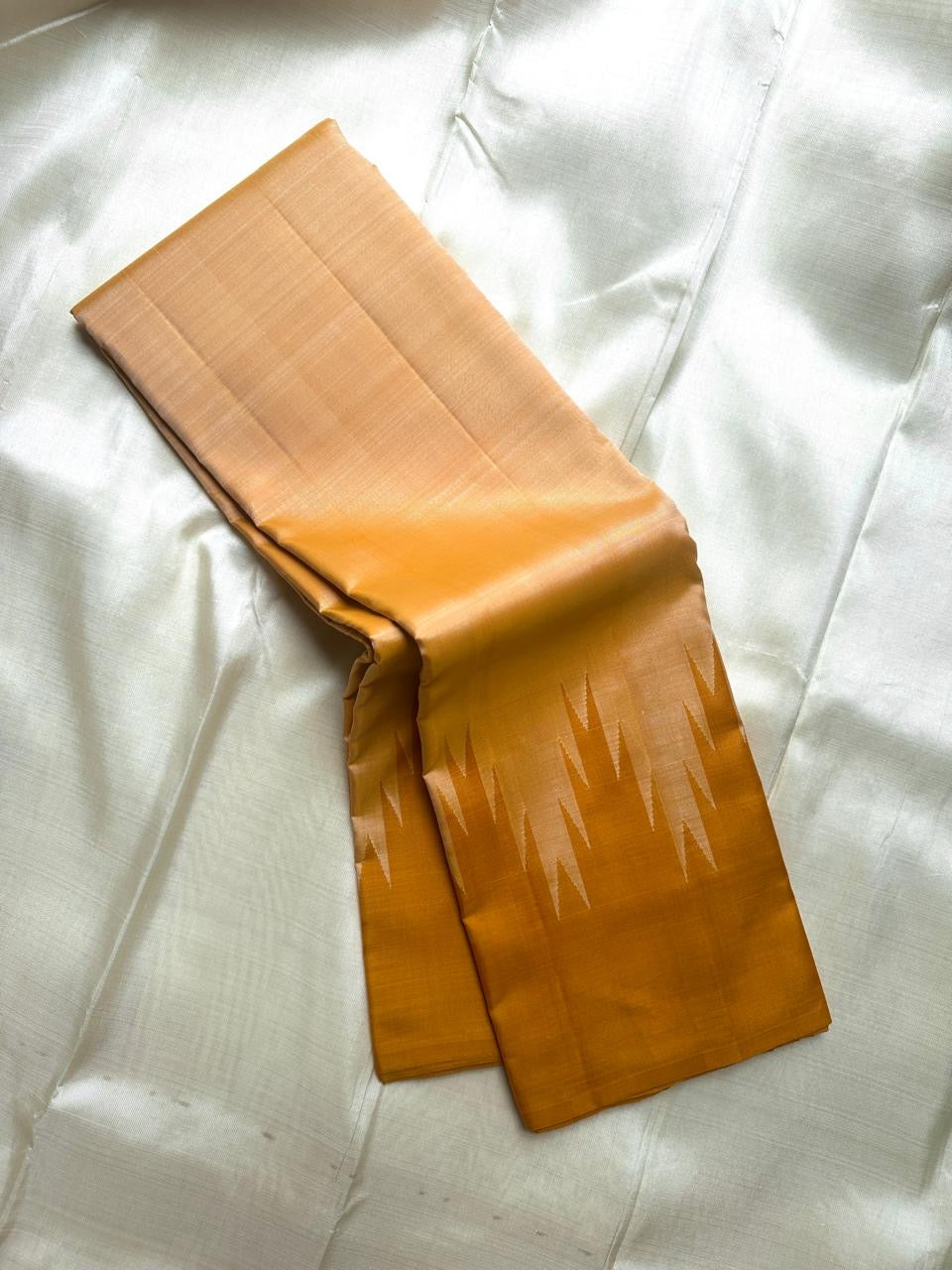 Draped mustard and beige Pure Kanchipuram Silk Saree showing geometric temple motif border and smooth silk sheen