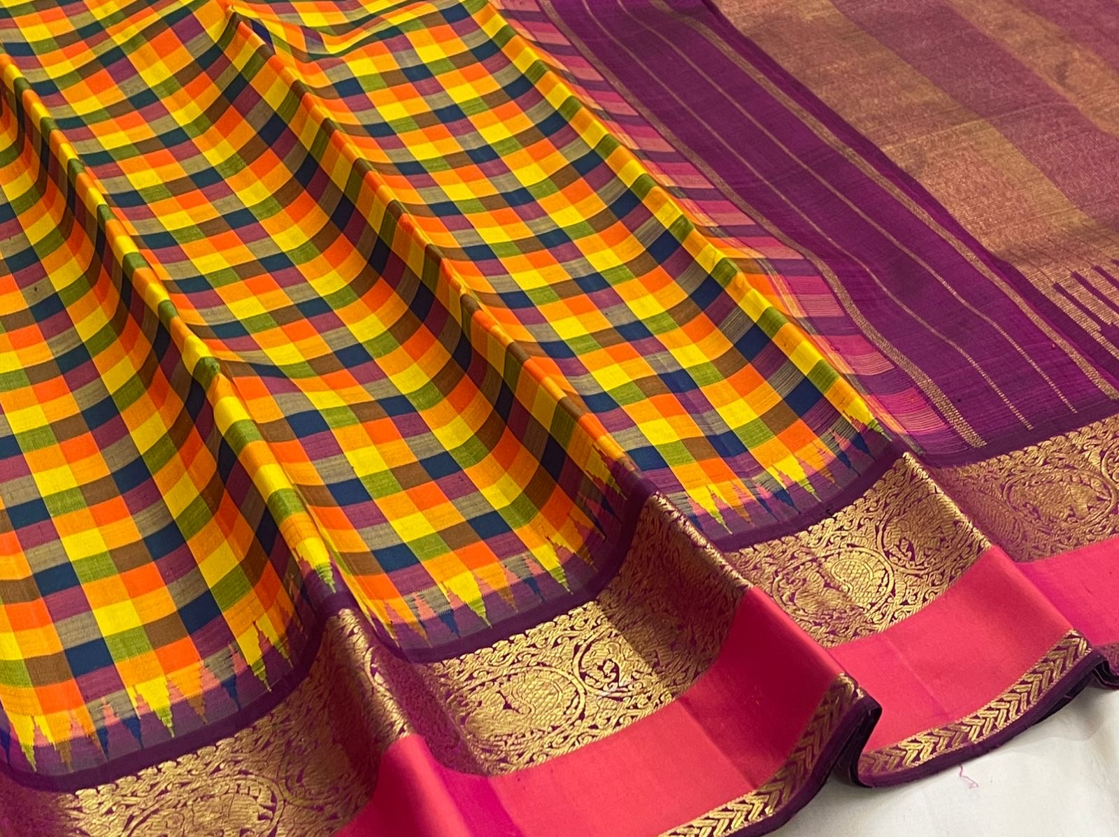 Pure Kanchipuram silk saree draped to highlight checked body and ornate gold zari border with pink accent