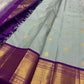 Draped dovetail grey Pure Kanchipuram Silk Saree with scattered gold buttas and purple zari border beside purple pallu
