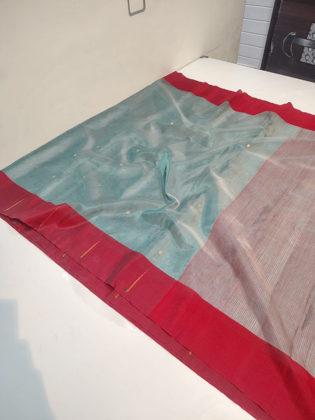Three-quarter view of mist blue Chanderi Tissue Silk saree with crimson border and gold-toned dots