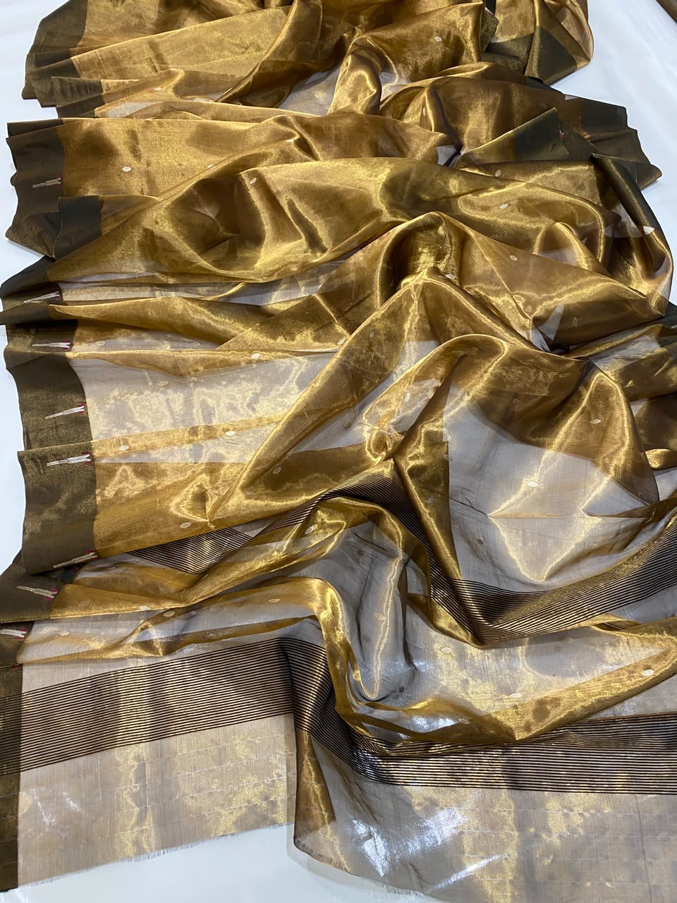 Close view of sheer Antique Gold Tissue Silk Chanderi with spaced buttas and olive border motifs with pink accents