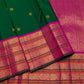 Close view of circular and stylised gold zari buttas arranged across the deep green silk body.