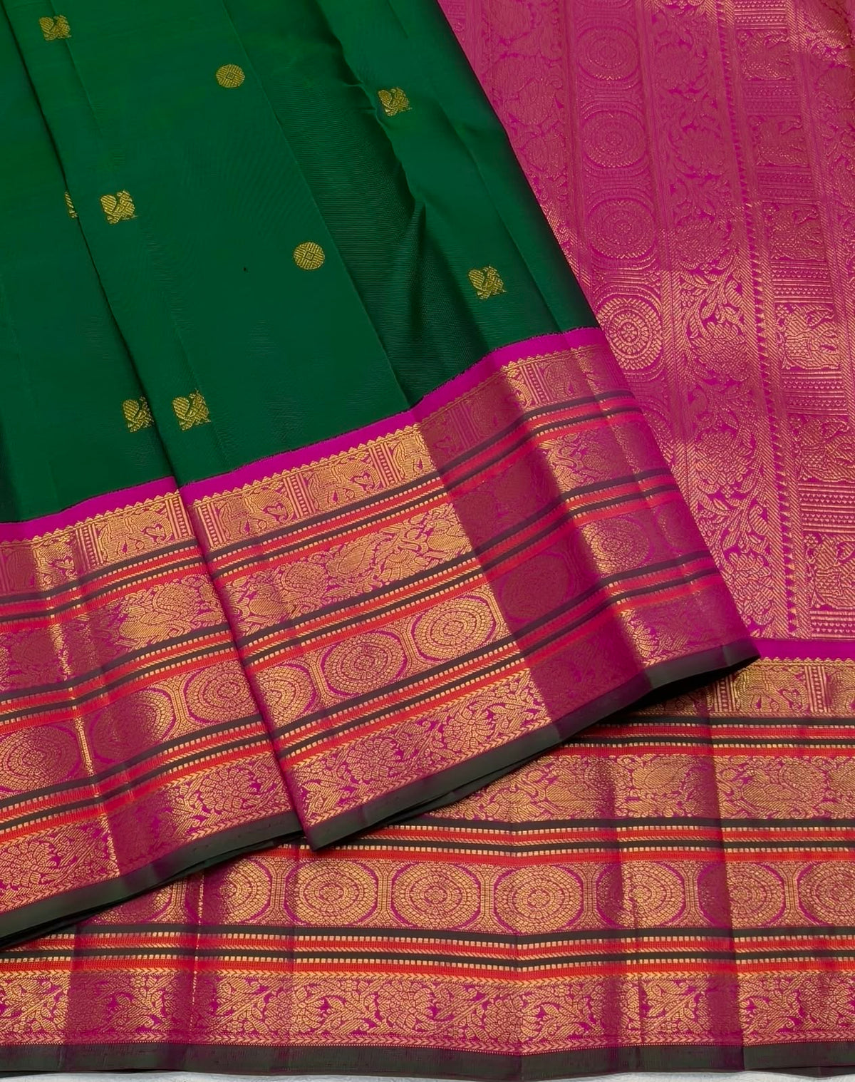 Close view of circular and stylised gold zari buttas arranged across the deep green silk body.