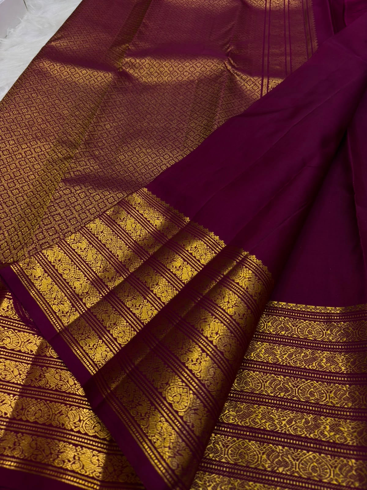 Deep cherry red Kanjivaram saree showing the contrast between its circular body buttas and rich gold pallu.