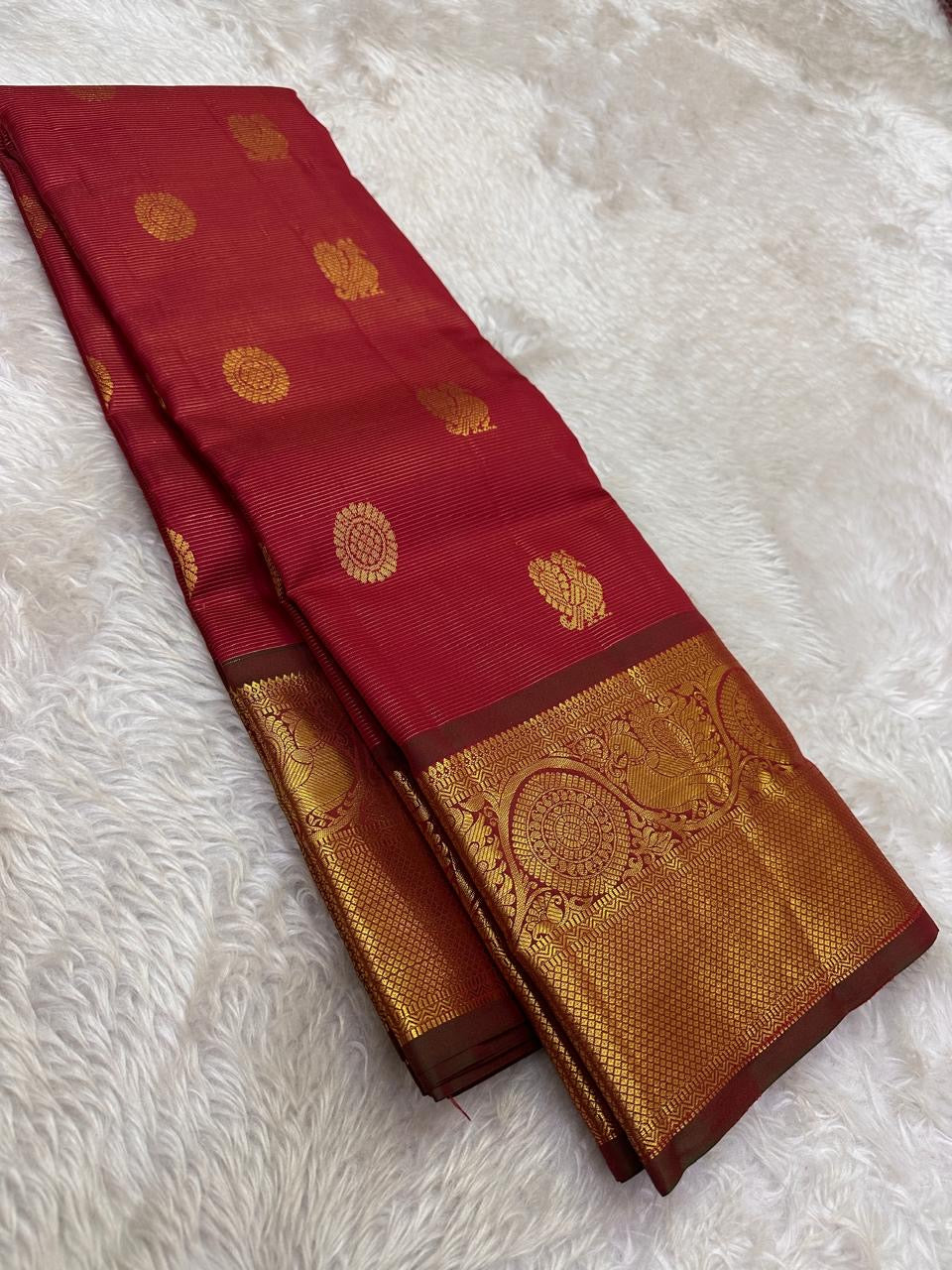 Front view of bright vermilion red with a luminous petal pink pallu Kanchipuram silk saree with small zari border and rich pallu.
