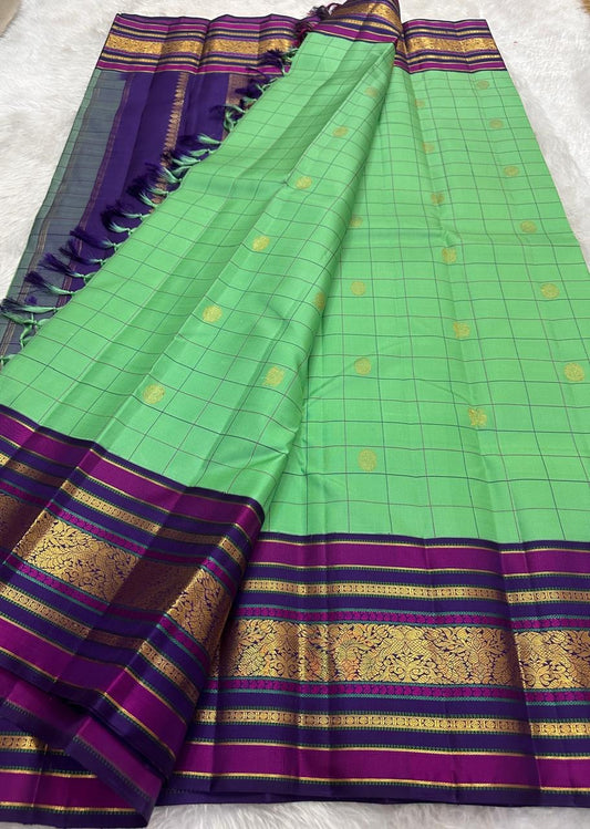 Pure Kanchipuram silk saree with kanchi kattam checks in green silk body featuring gold zari buttas and purple blue rettapet border
